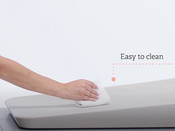 Woman wiping down a grey easy to clean changing mat with cloth